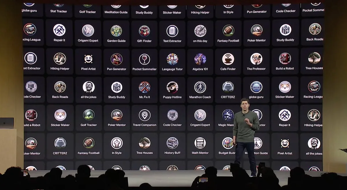 Presenter onstage before a large grid of assistant icons and names, with audience silhouettes in the foreground.